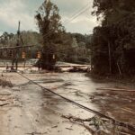 man walking down flooded road among downed powerlines