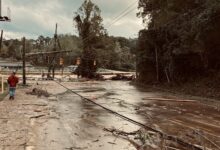 man walking down flooded road among downed powerlines