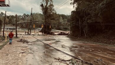 man walking down flooded road among downed powerlines