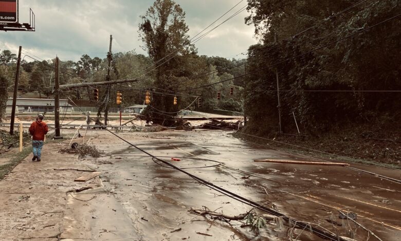 man walking down flooded road among downed powerlines