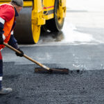 The road workers' working group updates part of the road with fresh hot asphalt and smoothes it for repair.